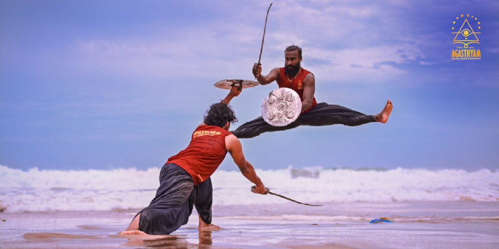Kalaripayattu practitioners demonstrating sword and shield combat technique on the beach